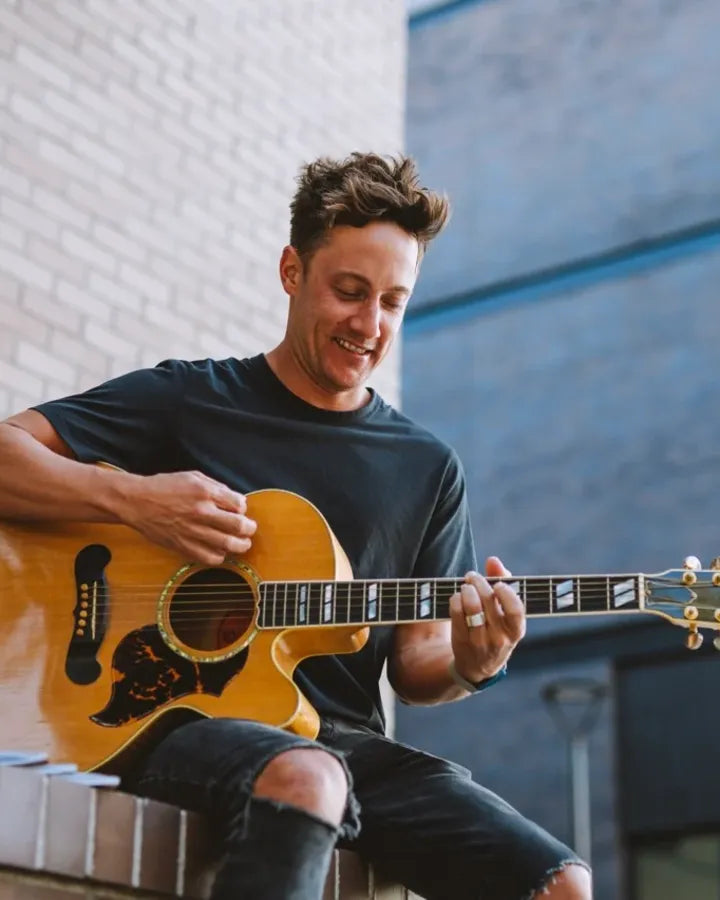 Jeffrey Kunde playing an acoustic guitar