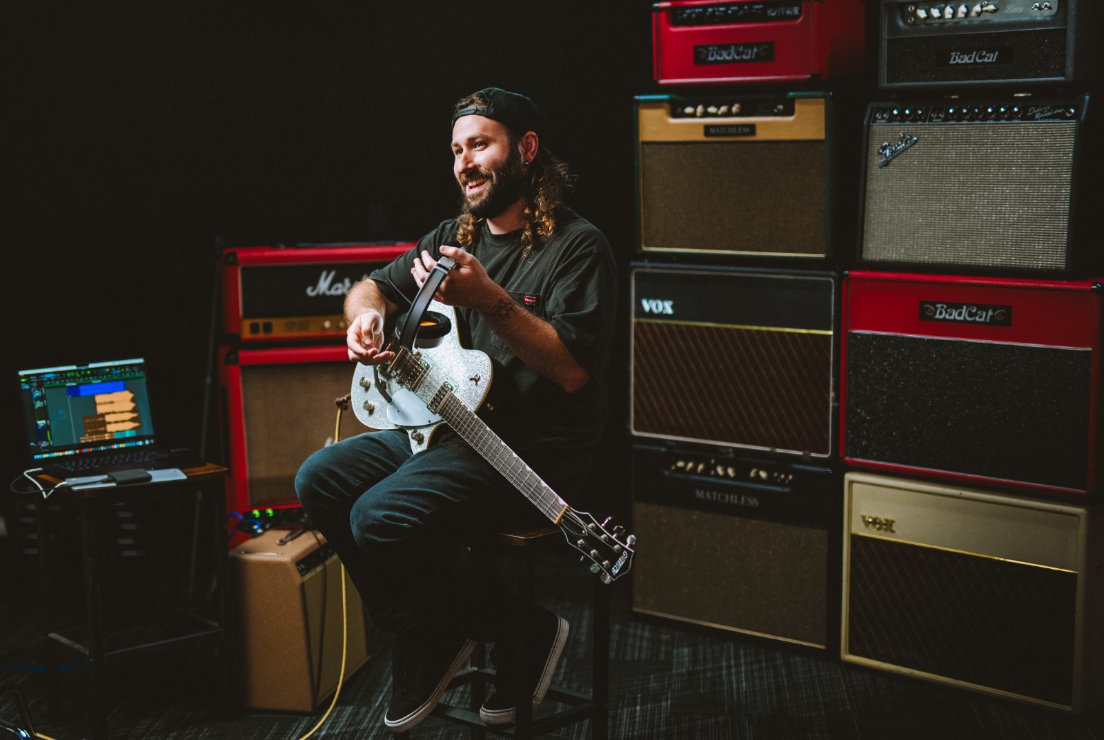 Jamie with his guitar in front of a wall of tube amps